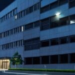 Edificio corporativo moderno con luces encendidas rodeado de vegetación, reflejando inversión global en tecnología.