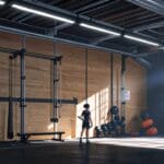 Interior de un gimnasio de escalada con equipos tecnológicos y gráficos de rendimiento en pantallas