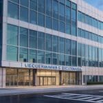 Fachada moderna de oficinas tecnológicas con símbolos digitales de entrega en pantalla gigante