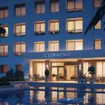 Imagen de un moderno hotel sostenible rodeado de vegetación exuberante al atardecer.