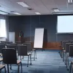 Sala de conferencias moderna con pantallas digitales y asistentes atentos