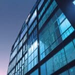 Edificio moderno y tecnológico iluminado por la luz del día capturado desde una perspectiva baja.