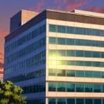 Vista aérea de un moderno edificio corporativo en un entorno urbano al atardecer