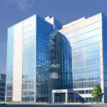 Vista panorámica de un edificio corporativo moderno al amanecer, rodeado de tecnología innovadora.