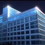 Edificios corporativos modernos iluminados por la luz del amanecer, representando crecimiento empresarial.