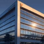 Edificio corporativo moderno con logotipo de banco iluminado al atardecer