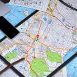 Imagen de un escritorio moderno con laptop y smartphone mostrando mapas digitales