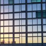 Edificio moderno en Santiago con el amanecer reflejándose en sus ventanas.