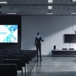 Salón de conferencias moderno con pantallas digitales y asistentes observando presentaciones tecnológicas