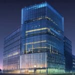 Moderno edificio de oficinas con fachada de cristal en una ciudad tecnológica al amanecer