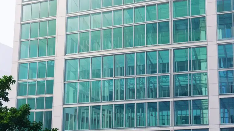 Edificio moderno con fachada de vidrio rodeado de áreas verdes, representando innovación tecnológica.