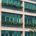 Imagen de un moderno edificio de oficinas tecnológicas rodeado de plantas de microalgas en un día soleado
