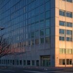 Fachada de un moderno edificio de oficinas en Santiago al atardecer, con una estética tecnológica y vanguardista.