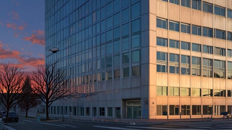 Fachada de un moderno edificio de oficinas en Santiago al atardecer, con una estética tecnológica y vanguardista.