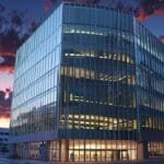 Un moderno edificio de oficinas de diseño arquitectónico innovador iluminado al atardecer en una ciudad europea.