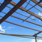Primer plano de una innovadora planta de producción rodeada de madera y metal bajo un cielo despejado