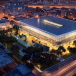 Vista aérea de un moderno centro de eventos rodeado de naturaleza en un atardecer iluminado.