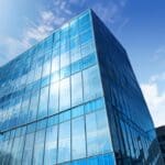Moderno edificio corporativo con fachada de vidrio reflejando el cielo azul