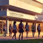 Moderno campus universitario al atardecer con estudiantes interactuando