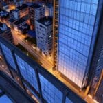 Vista aérea de edificios modernos en Bogotá iluminados al atardecer, reflejando un ambiente tecnológico.