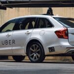 Un auto de Uber en una ciudad moderna con pantallas publicitarias encendidas en el interior.