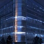 Imagen de un moderno edificio corporativo al anochecer con luces que reflejan un ambiente tecnológico