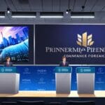 Conferencia de prensa corporativa con logos modernos y gráficos financieros en pantalla