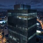 Vista aérea de un edificio moderno de oficinas en Ciudad de México con luces encendidas al anochecer, simbolizando inversión y tecnología