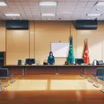 Sala de reuniones moderna con pantallas digitales y documentos sobre legislación tecnológica en una mesa de trabajo