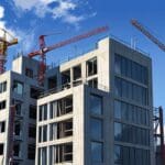 Edificios modernos en construcción rodeados de grúas bajo un cielo despejado