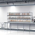 Primer plano de una instalación científica con tubos de ensayo y larvas en estudio, sobre una mesa blanca en un laboratorio moderno