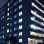 Vista moderna de un edificio residencial inteligente en entorno urbano, con iluminación cálida al anochecer