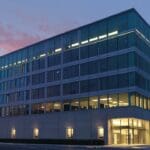 Edificio moderno de oficinas iluminado al anochecer, representando tecnología y negocios globales.