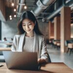 Retrato de una emprendedora joven trabajando frente a una laptop en un espacio de coworking moderno