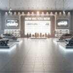 Sala moderna con autos usados exhibidos y pantallas interactivas sin presencia de personas.