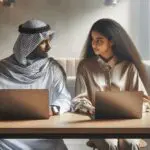 Dos mujeres jóvenes colaborando frente a laptops en un espacio de coworking moderno.