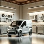 Fotografía en un taller moderno con una camioneta eléctrica compacta en primer plano y herramientas tecnológicas al fondo.