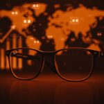 Gafas inteligentes Ray-Ban Display de Meta con iluminación naranja y metáfora visual de expansión internacional detenida por alta demanda y falta de stock.