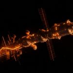 Estación espacial privada orbital iluminada en naranja y negro, simbolizando la transición comercial de NASA y los desafíos del mercado espacial orbital.
