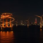 Parque eólico flotante frente a Tokio iluminado con tonos naranja y negro, representando el megaproyecto de energía renovable en Japón para 2035.