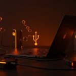 Laptop con puerto USB-C y cargadores GaN iluminados en tonos naranjas y negros, simbolizando la carga rápida y la innovación tecnológica para startups en la UE 2026.