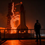 Ingeniero aeroespacial observando la plataforma de lanzamiento del programa Artemis de la NASA, representando los desafíos de infraestructura en el NewSpace.